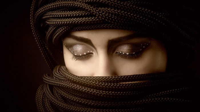 Woman covered in dark ropes with dramatic eye makeup