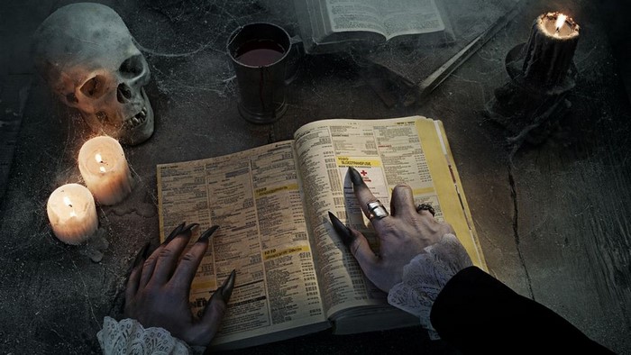 Vampire reading a book with a skull and candles