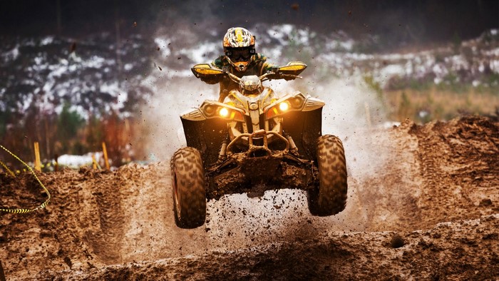 Man riding a dirt quad bike jumping over mud