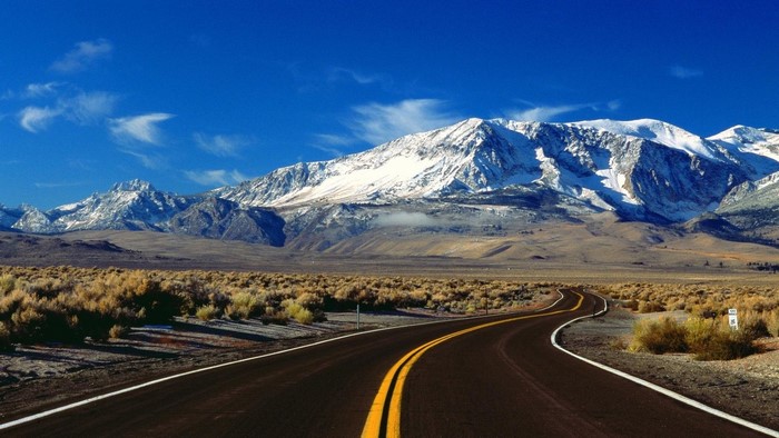 Desert Road Leading to Snow-Capped Mountains