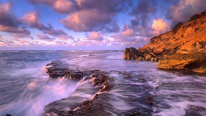 Ocean waves crashing on rocky shore at sunset