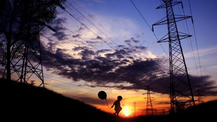 Child with balloon near power lines at sunset