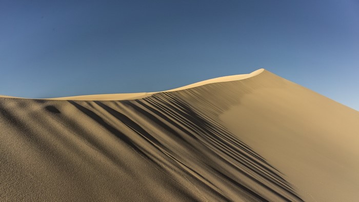 Desert sand dune under a clear blue sky