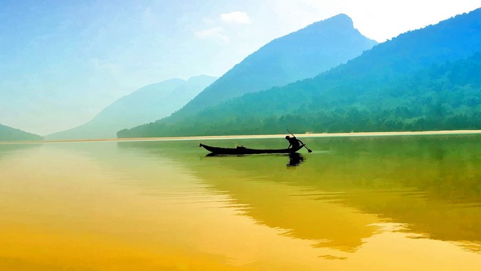 Fisherman in a boat on a lake with mountains