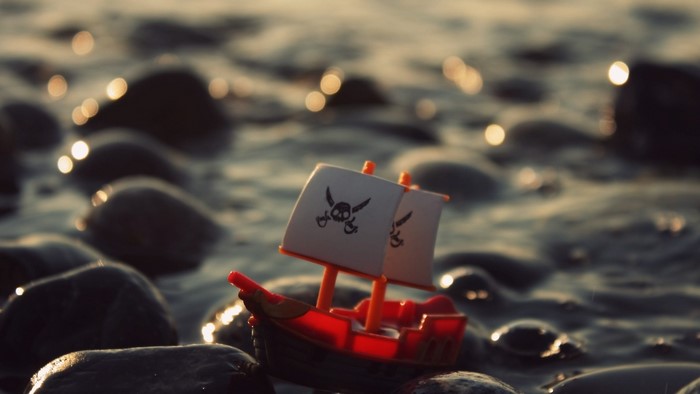 Toy pirate ship with skull and crossbones sails on rocks
