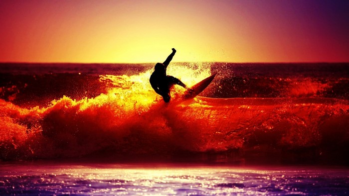 Surfer riding a wave at sunset