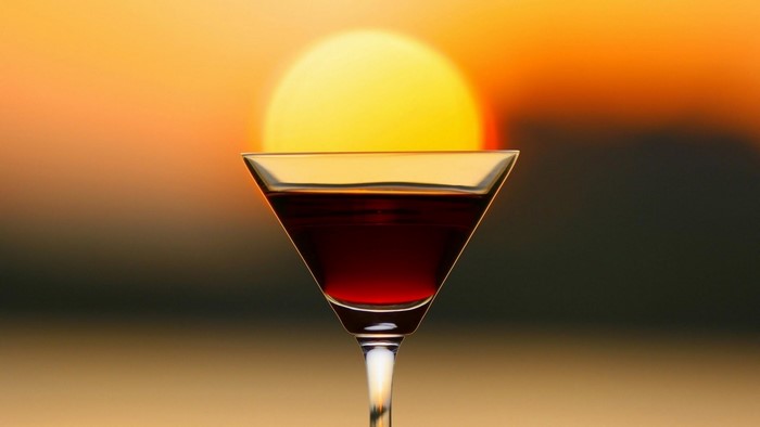 Cocktail glass with red liquid at sunset