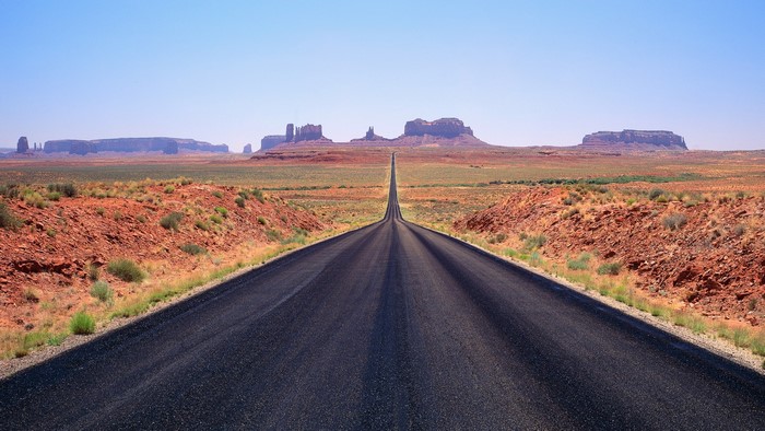Desert road leading to Monument Valley mesas