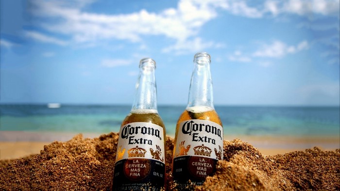 Two Corona Extra bottles on a sandy beach