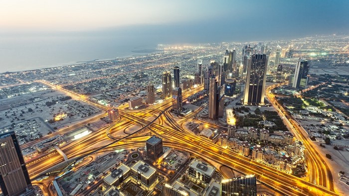 Aerial view of Dubai cityscape at night with illuminated highways