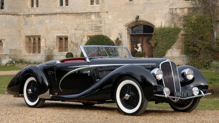 Black Delahaye 135 Ms Cabriolet parked in front of a stone building