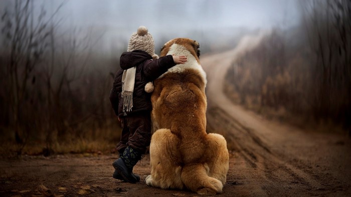 Child and dog on a dirt road