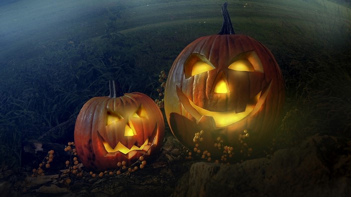 Two carved Halloween pumpkins glowing in the dark