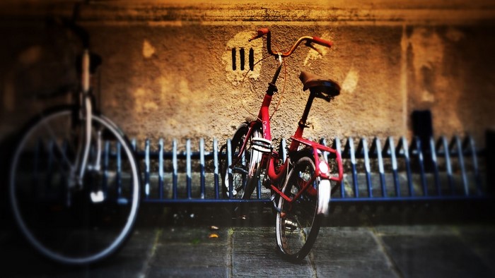 Two bicycles parked in front of a textured wall