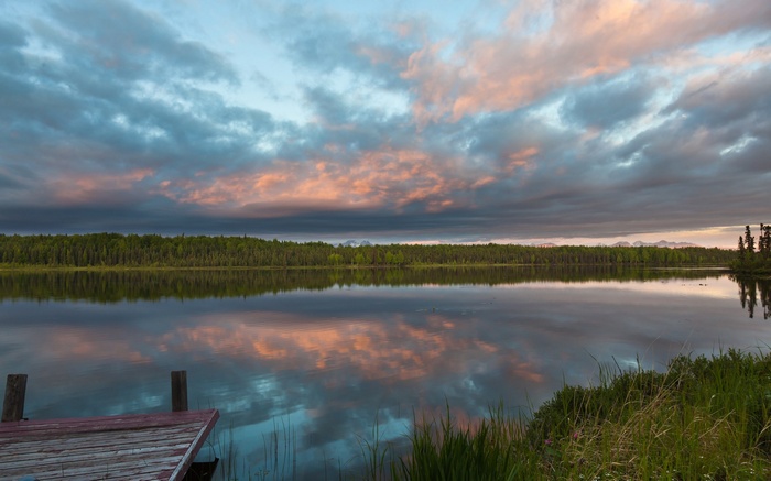 Wooden dock on a calm lake at sunset