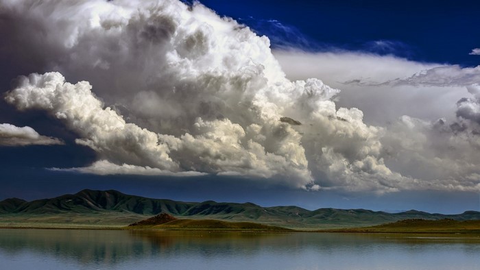 Dramatic storm clouds over a lake and mountains