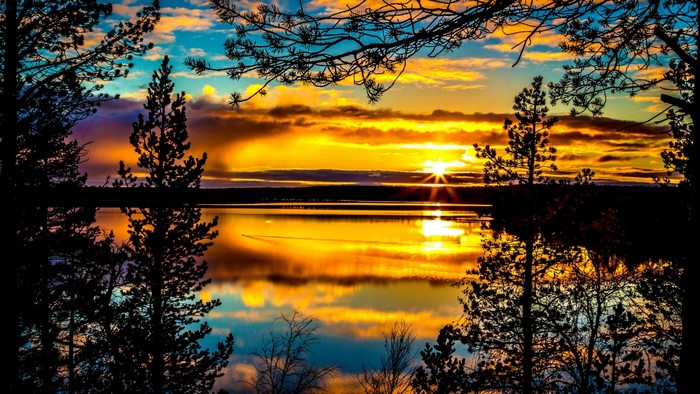 Sunset over a lake with trees in silhouette