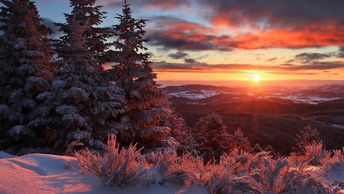 Winter sunset over snowy mountains and trees