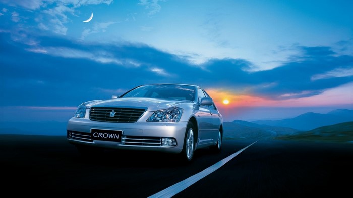 Silver Toyota Crown on a road at sunset