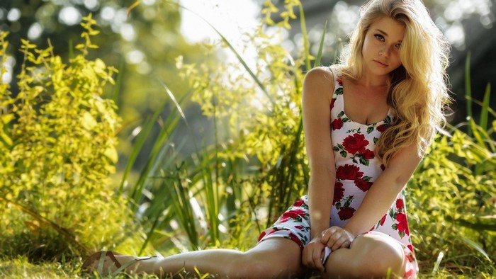Young woman in a floral dress sitting in a garden