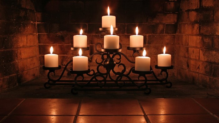 Candles on a wrought iron stand in a fireplace