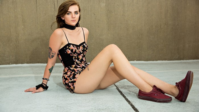 Young woman with tattoos wearing a floral romper and Vans