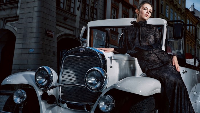 Woman in black dress leaning on vintage car