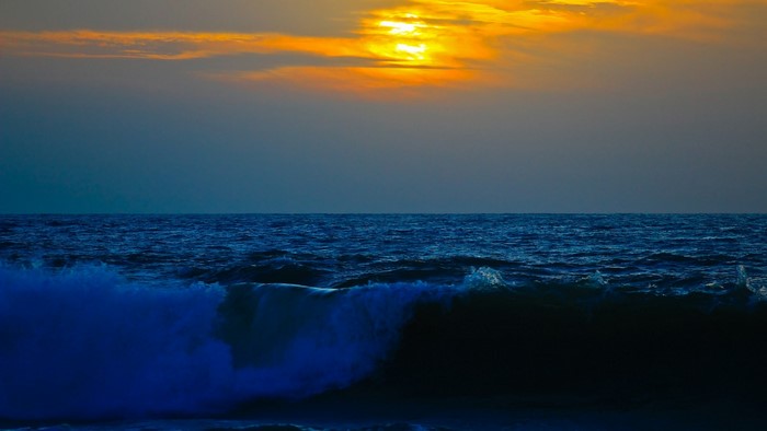 Sunset over the ocean with a breaking wave