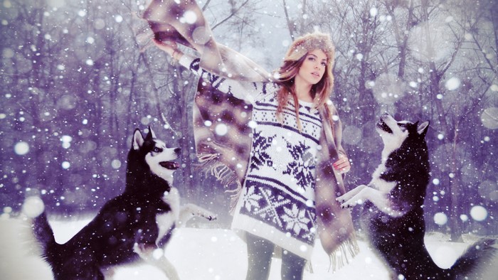 Girl with husky dogs in a snowy forest