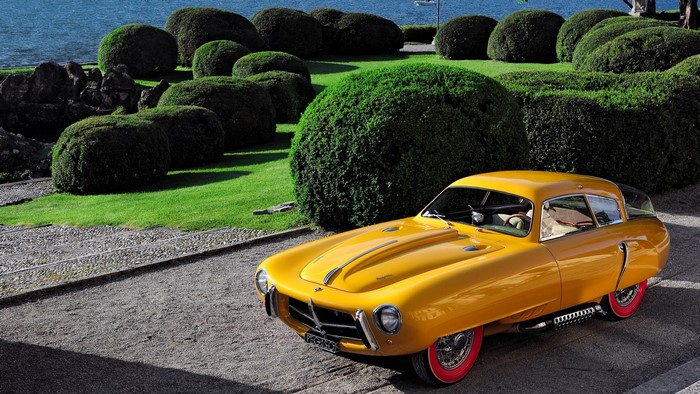 Yellow Pegaso Z 102 by a lake with manicured bushes