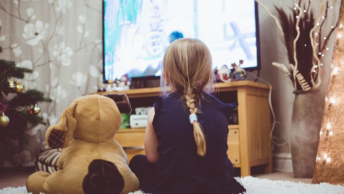 Child watching TV with stuffed animal