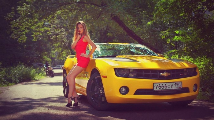 Woman posing with yellow Chevrolet Camaro