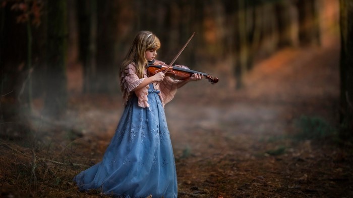 Girl playing violin in a forest