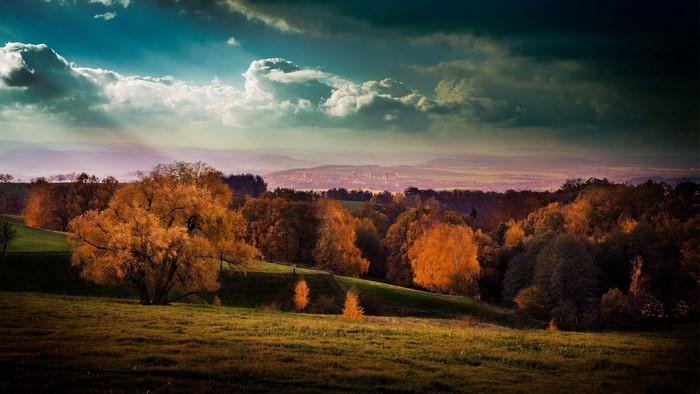 Autumn landscape with dramatic clouds over a distant city