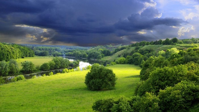 Green valley with river and stormy sky