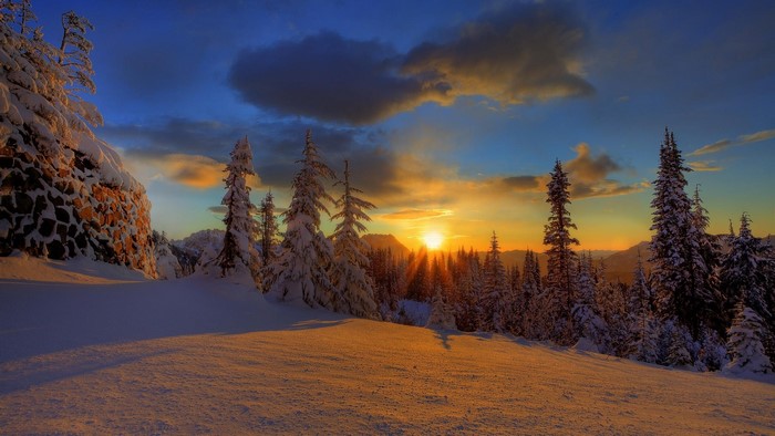 Sunset over snow-covered mountains and trees