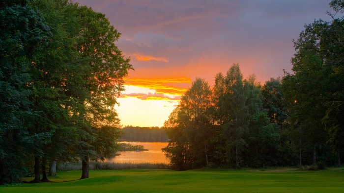 Sunset over a lake with trees and a golf course