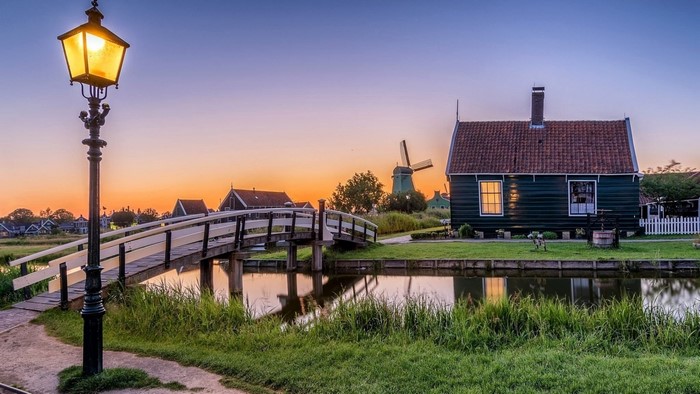 Dutch village with windmill and canal at sunset