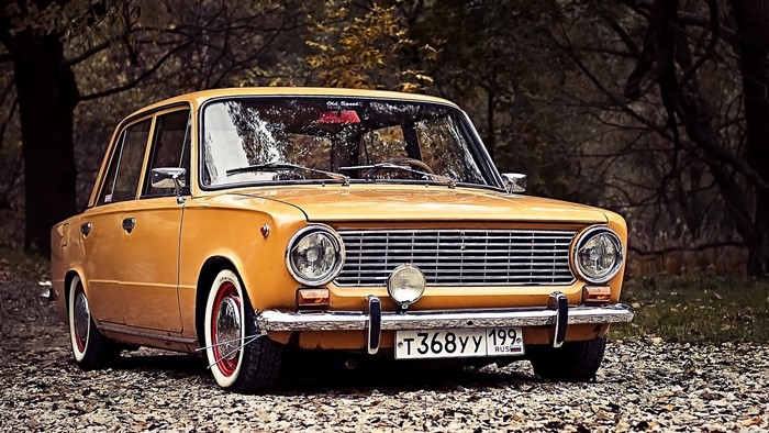 Yellow classic car parked on a gravel road