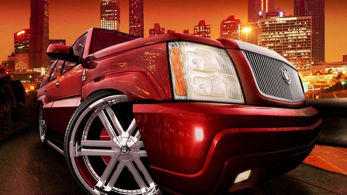 Red Cadillac Escalade with large rims in city at night