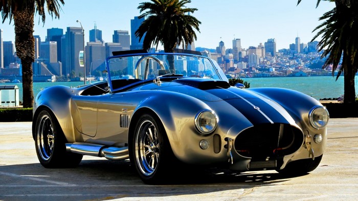 Silver Ford Cobra convertible with San Francisco skyline