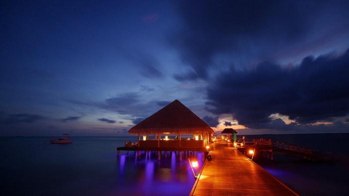 Pier with thatched roof huts at dusk