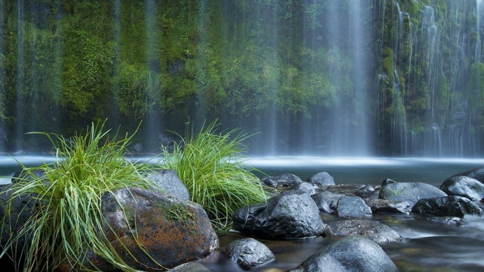 Waterfall with mossy rocks and grass