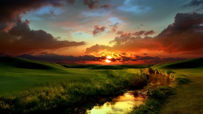 Sunset over rolling green hills with a stream