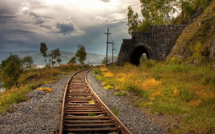 Train tracks leading to a stone tunnel entrance