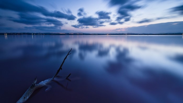 Calm lake at dusk with reflections and clouds