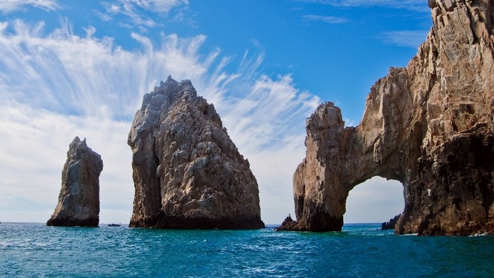 Sea stacks and arch in the ocean under a cloudy sky