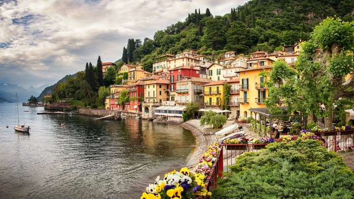 Colorful Italian village on a lake with a sailboat