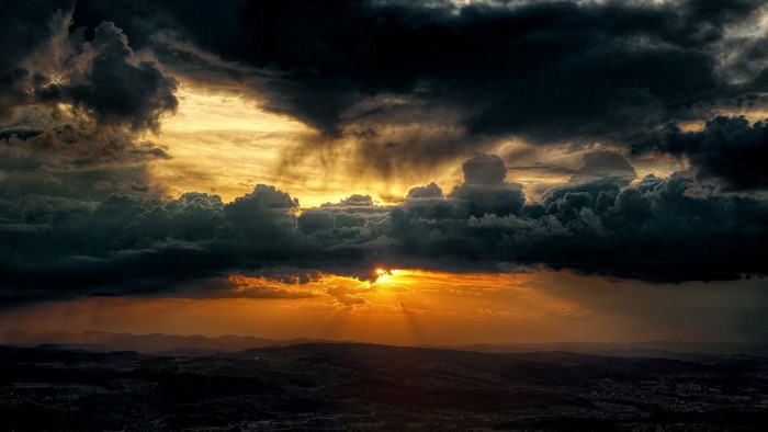 Dramatic Sunset with Stormy Clouds Over Hills