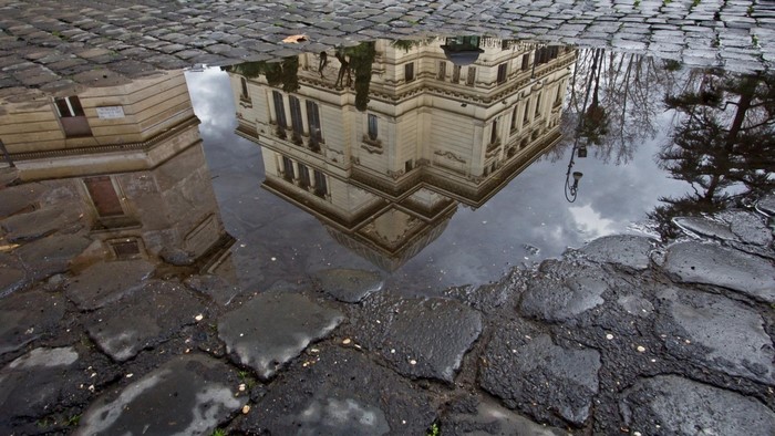 Reflection of building on wet cobblestone street